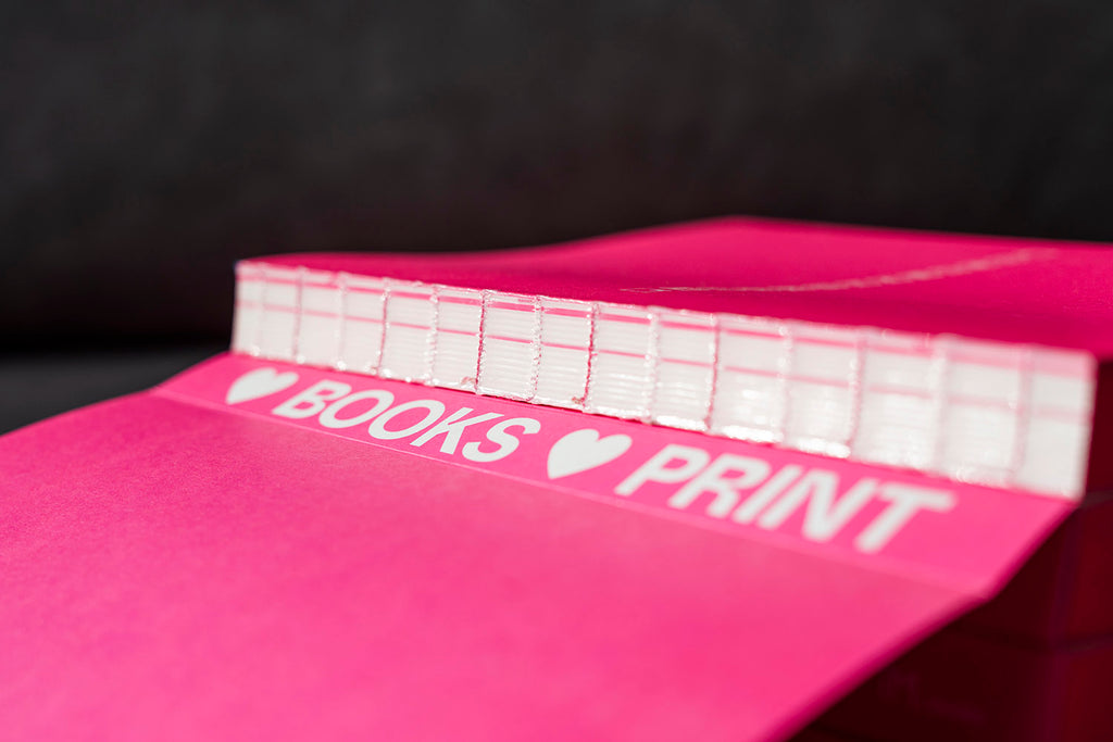 Encuadernación suiza del libro InDesign Lab, escrito y diseñado por Salva Cerdá. Se aprecia la encuadernación con hilo rosa y el rótulo «Love Books Love Print».